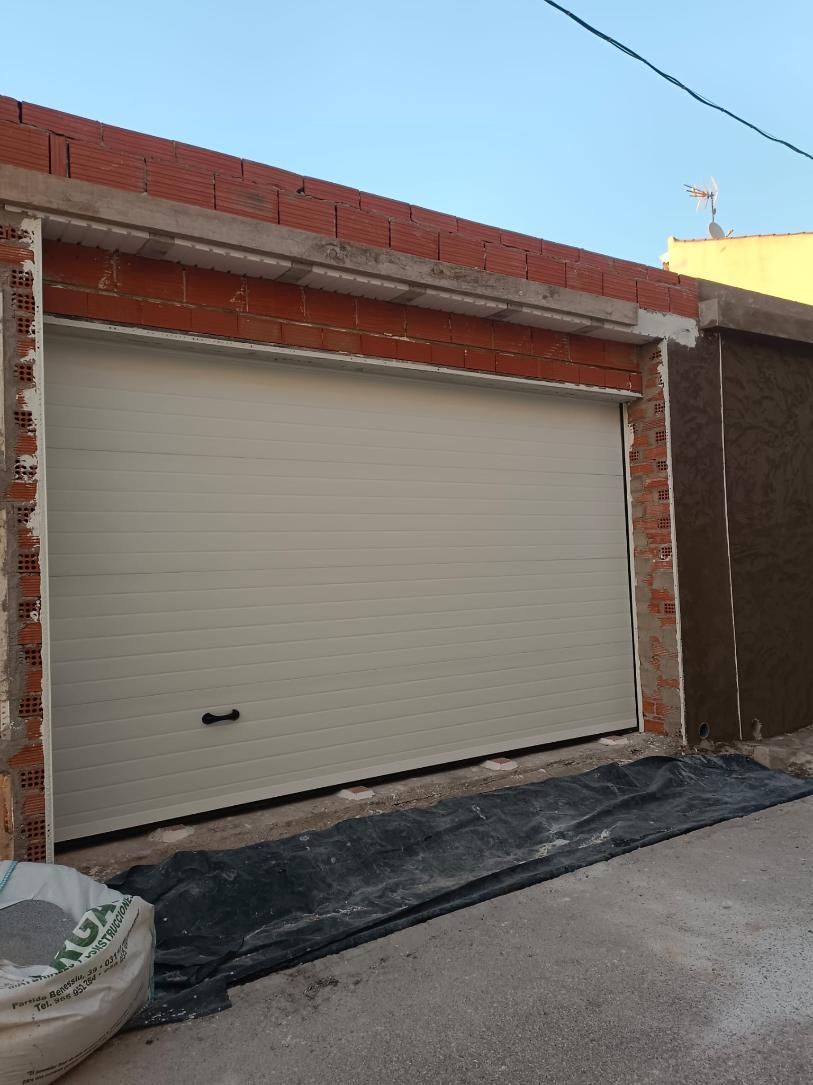 Puerta de garaje, color beige, en estructura de ladrillo y hormigón, en construcción.