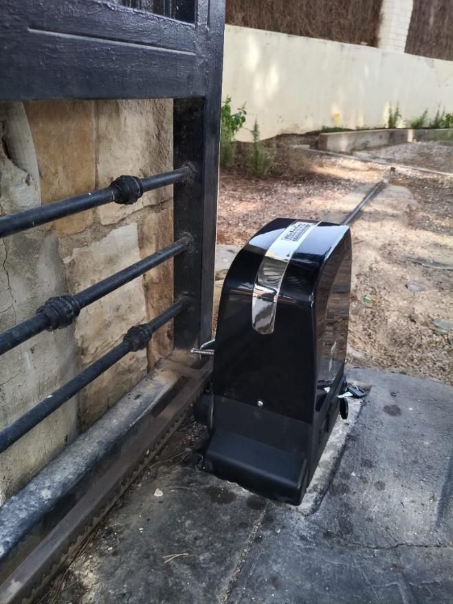 Abridor de puerta automático negro fijado a puerta de metal.