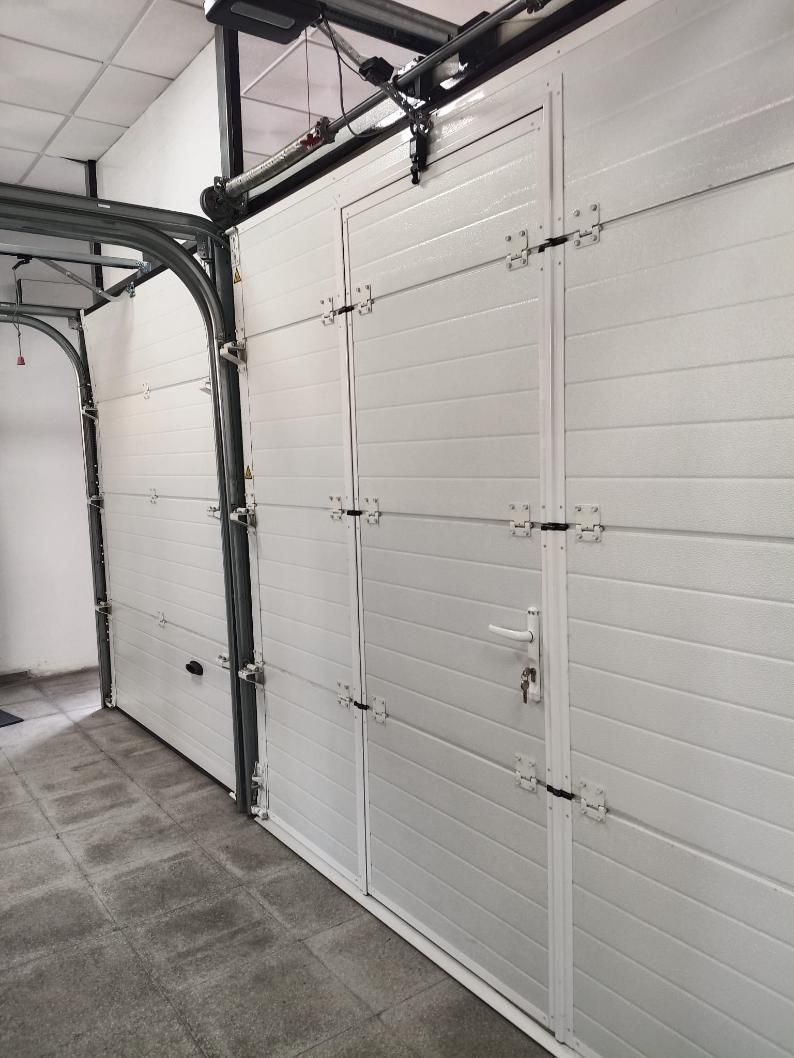 Puertas de garaje blancas con paneles horizontales. Se ven el sistema de rieles y los herrajes.