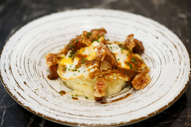 Un plato blanco cubierto con puré de patatas y carne sobre una mesa.