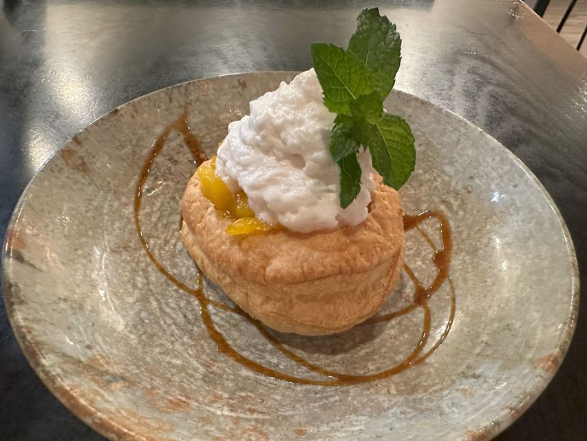 Un postre con crema batida y hojas de menta en un plato sobre una mesa.