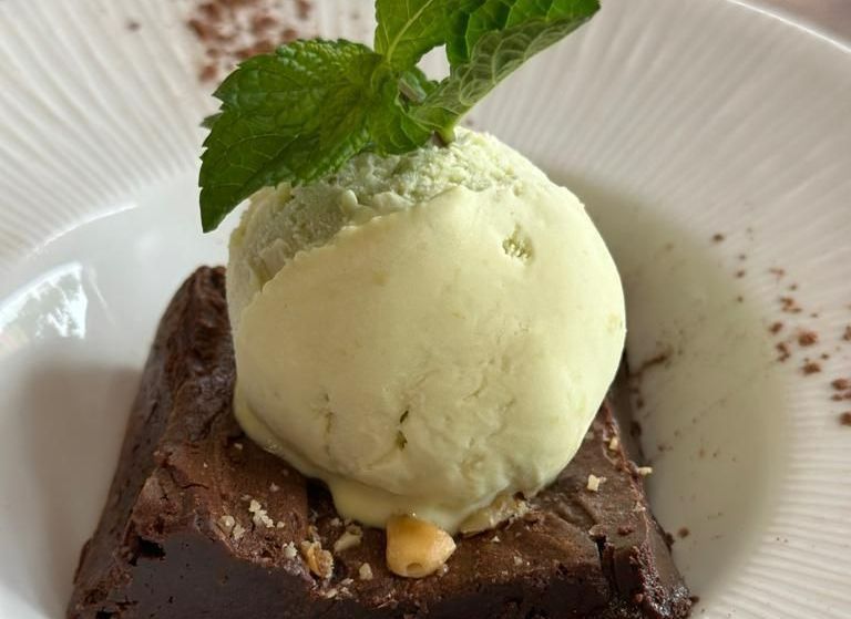 Un brownie con una bola de helado encima.