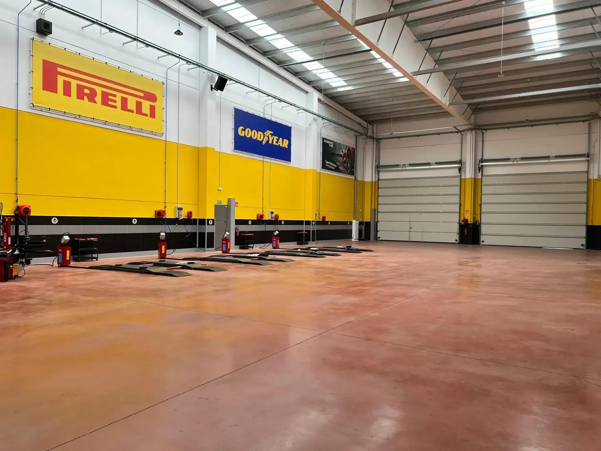 Un todoterreno marrón sobre un elevador de coches en un garaje, un mecánico trabaja cerca.