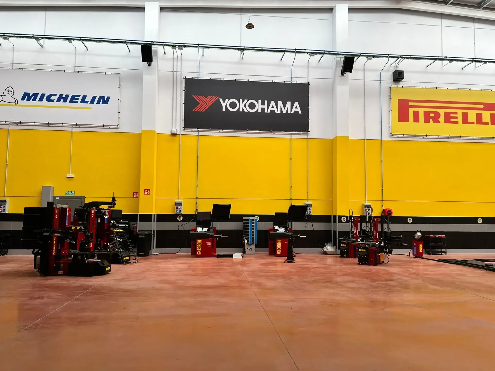 Un todoterreno marrón sobre un elevador de coches en un garaje, un mecánico trabaja cerca.