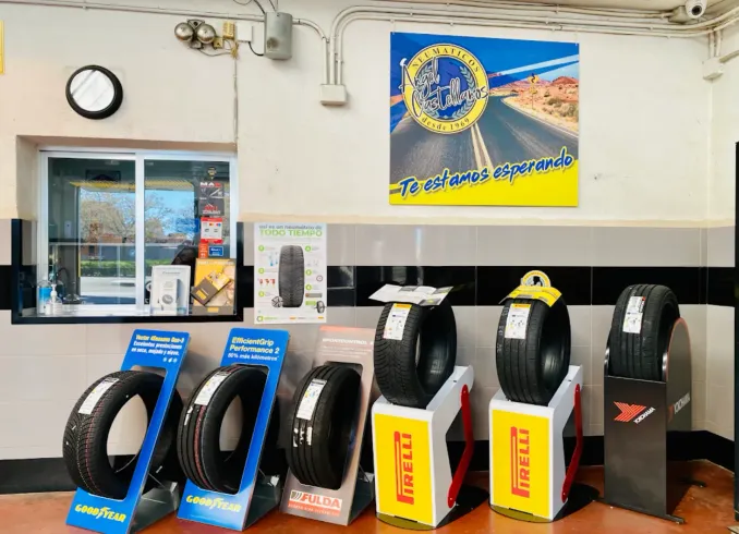 Neumáticos expuestos en una tienda, con un escaparate y un cartel que dice "Te estamos esperando".