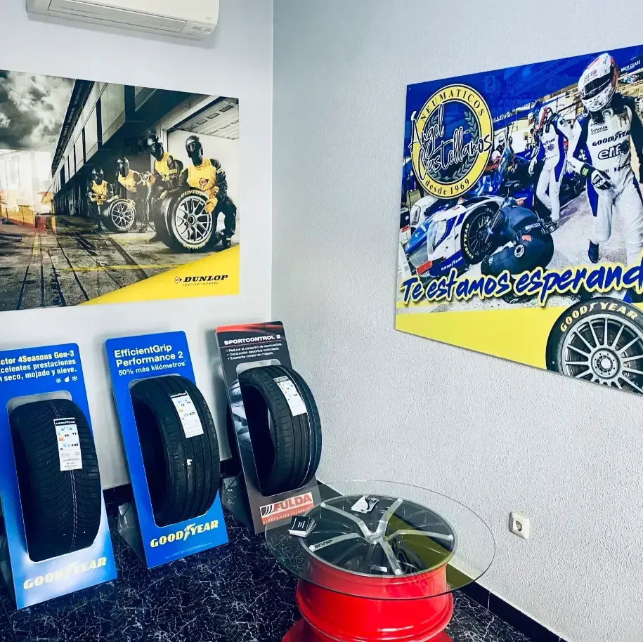 Neumáticos expuestos en una tienda, con carteles de coches de carreras y corredores en las paredes.
