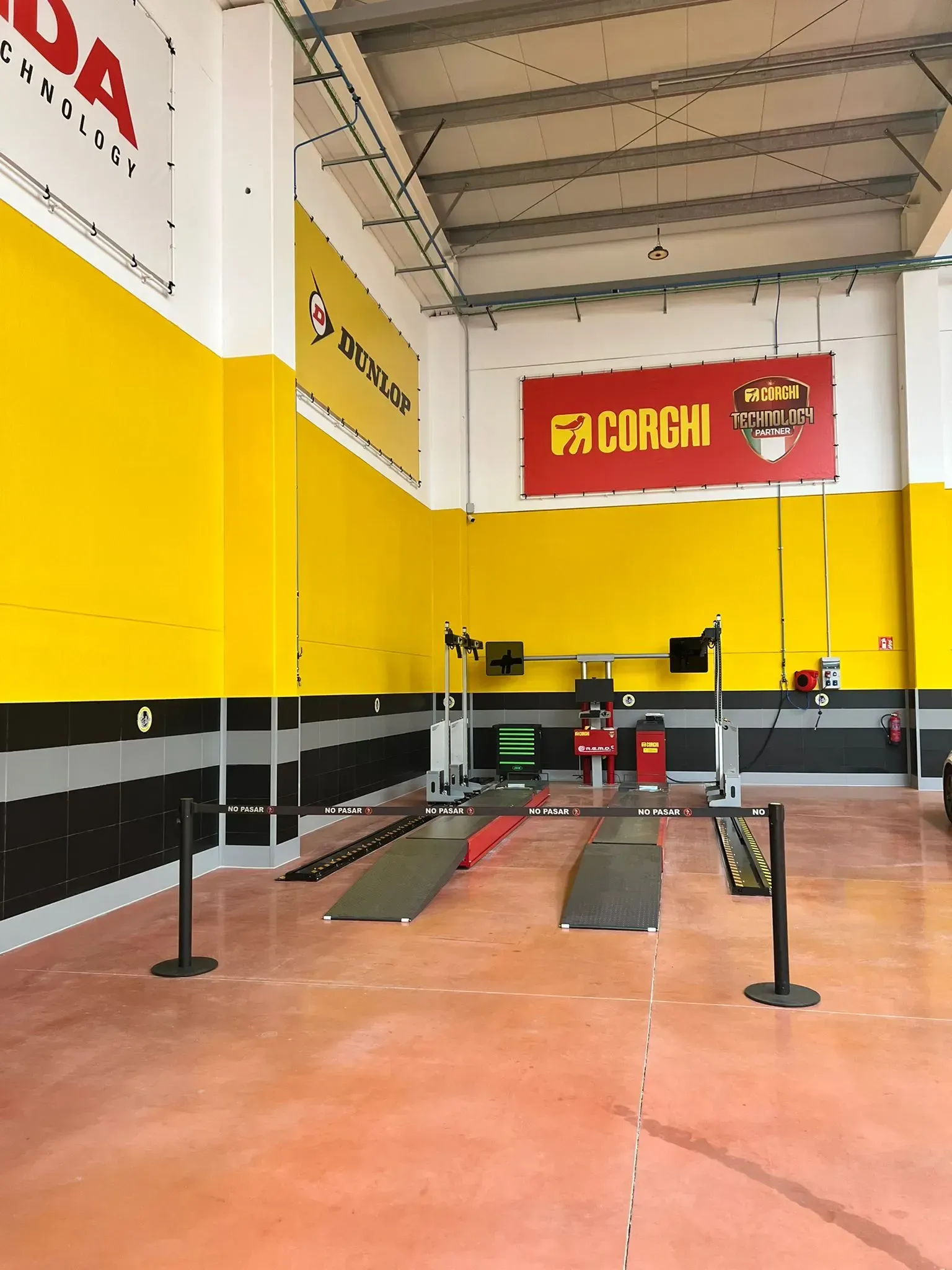 Un todoterreno marrón sobre un elevador de coches en un garaje, un mecánico trabaja cerca.