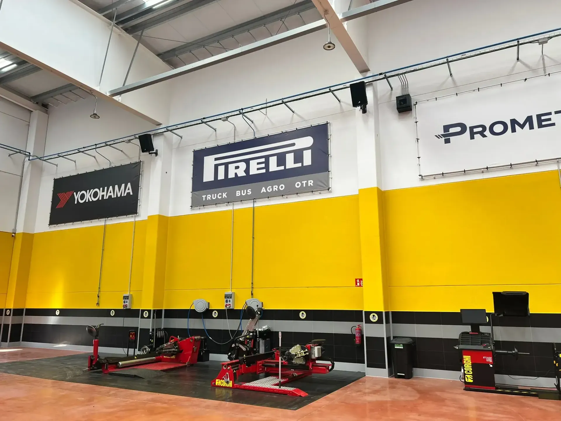 Un todoterreno marrón sobre un elevador de coches en un garaje, un mecánico trabaja cerca.