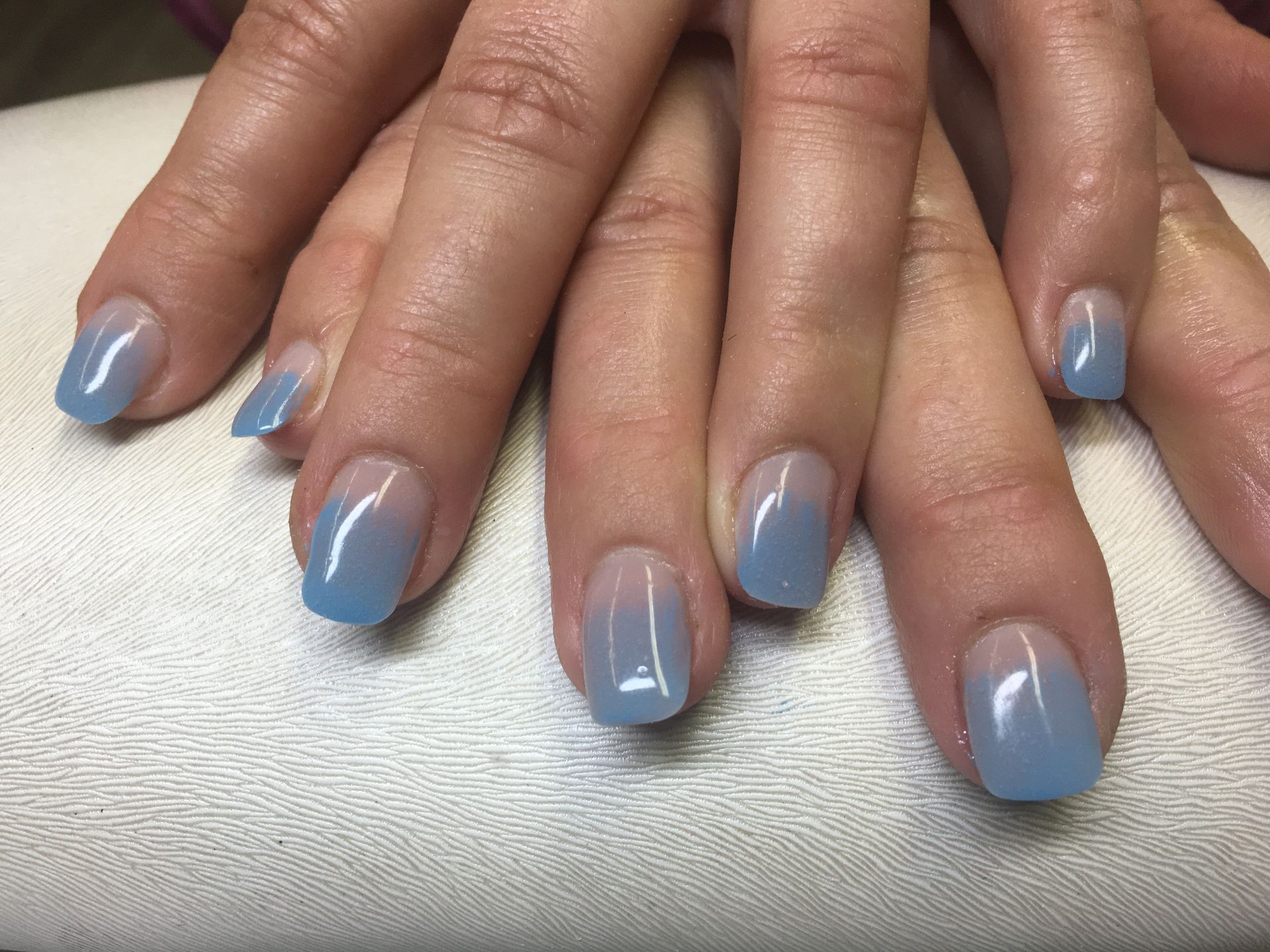 Elegante Maniküre in Hellblau mit glänzendem Gel-Lack auf kurzen, natürlich geformten Nägeln.