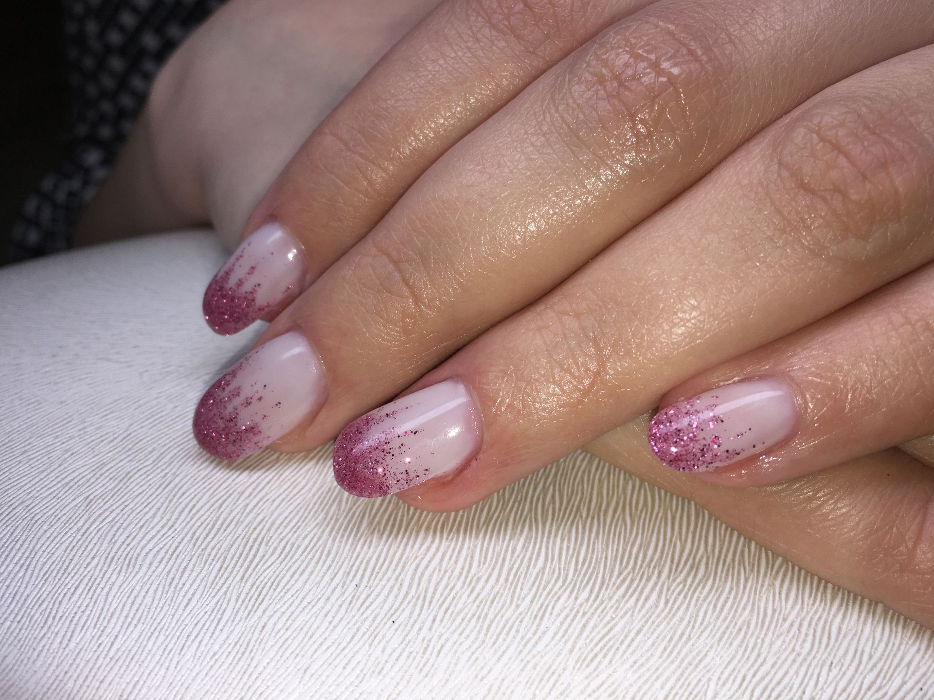 Nude Maniküre mit pinkem Glitzer-French auf kurzen, natürlich geformten Nägeln mit glänzendem Gel-Finish