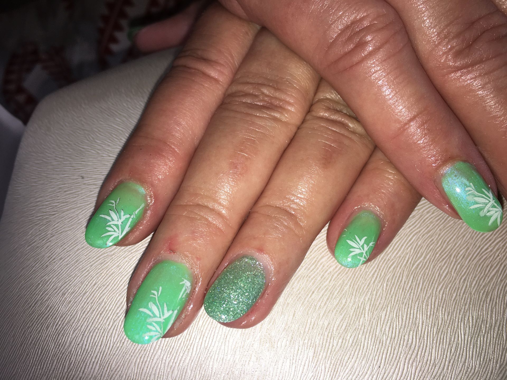 Grüne Glitzer Maniküre mit weißem Schneeflocken Nailart auf kurzen, rund gefeilten Nägeln.