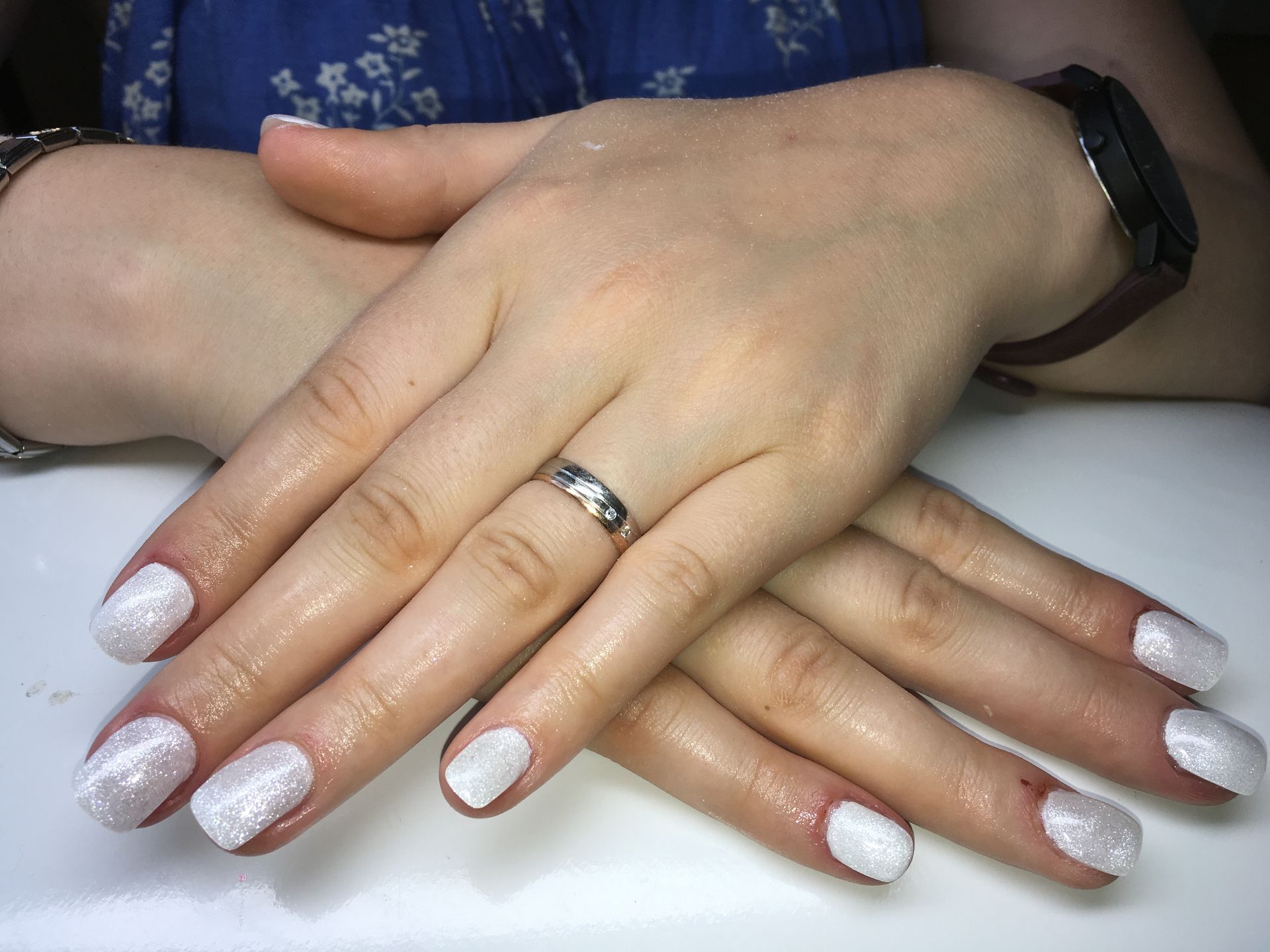 Elegante Nude-Maniküre mit weißem Glitzerverlauf auf mandelförmigen Nägeln und glänzendem Gel-Finish.