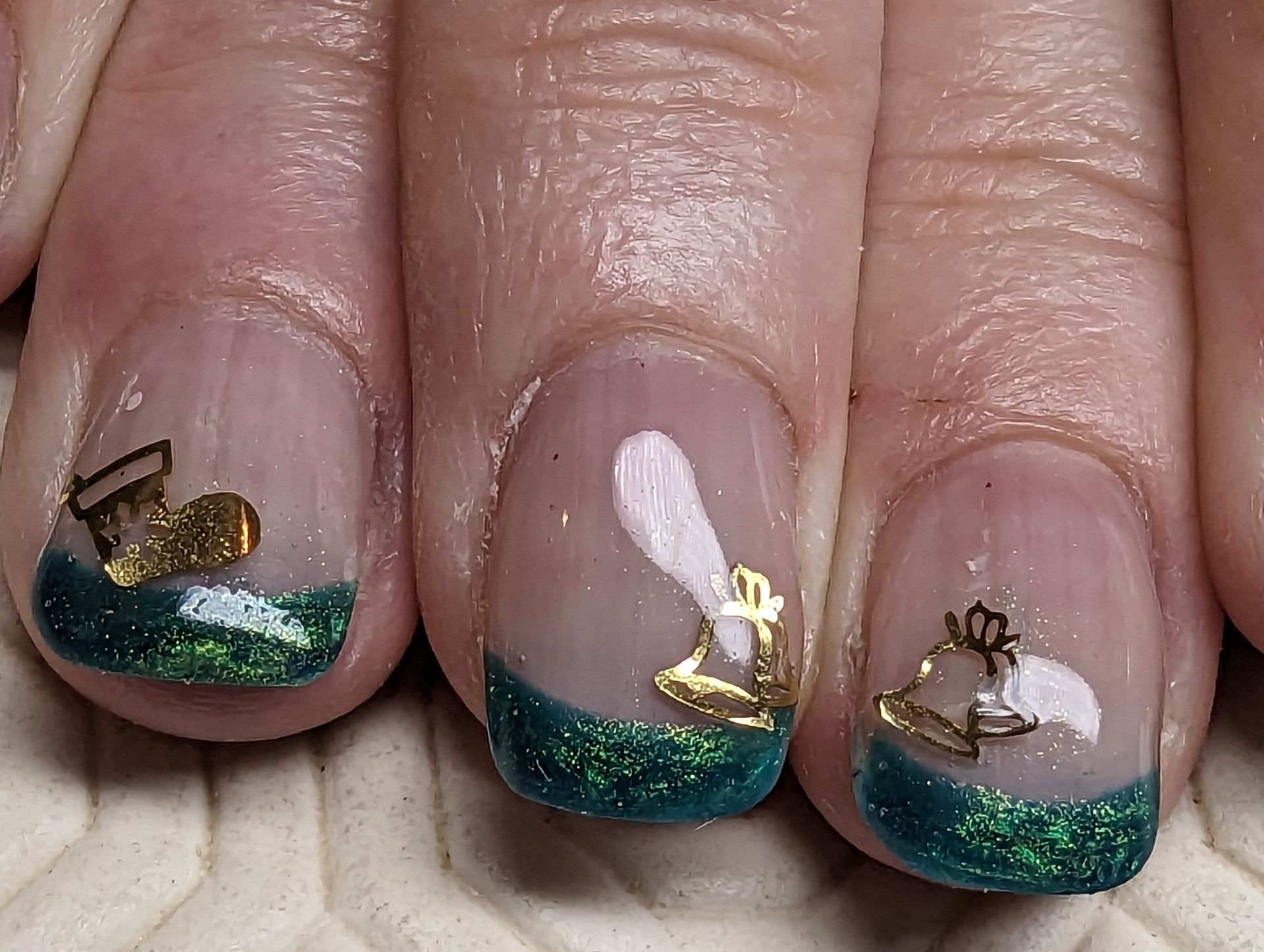 Nailart mit grünem Glitzer-French und goldenen Ornamenten auf natürlichen, glänzenden Nägeln.