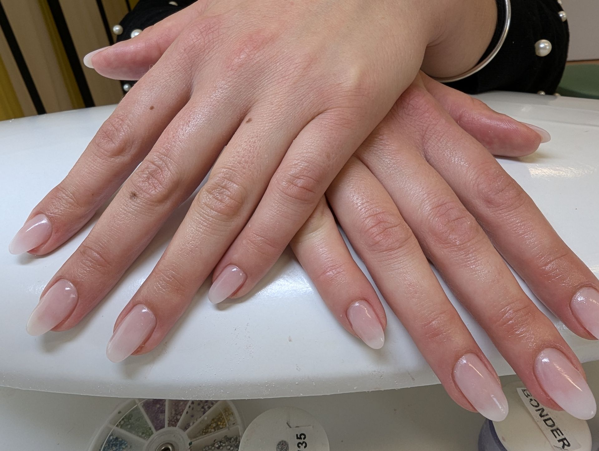 Natürliche Maniküre mit mandelförmigen Nude-Rosé Nägeln und glänzendem Gel-Finish auf gepflegten Händen.
