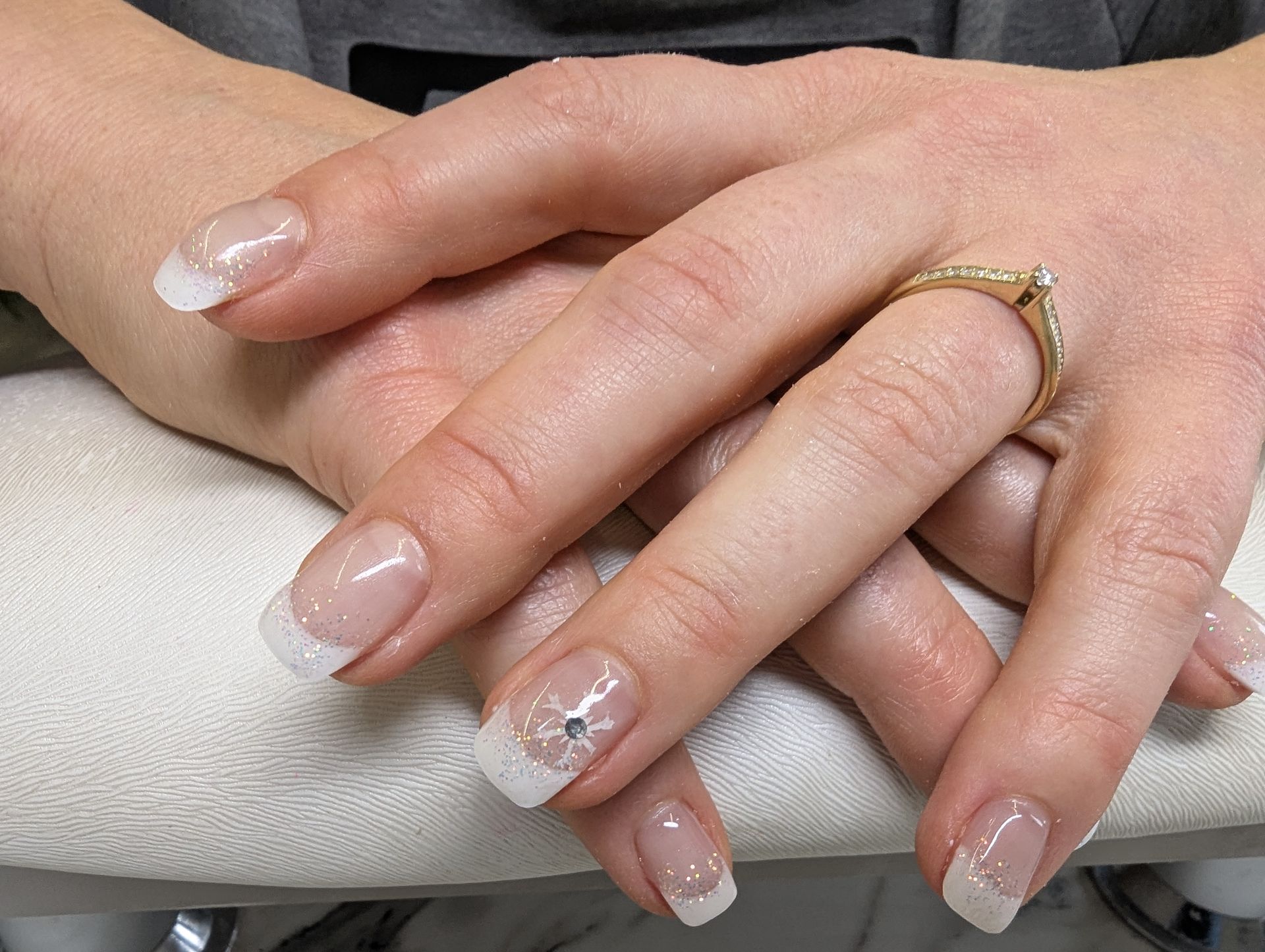 Natürliche French Maniküre mit zartem Nude-Ton und weißer Spitze auf gepflegten, mandelförmigen Nägeln.