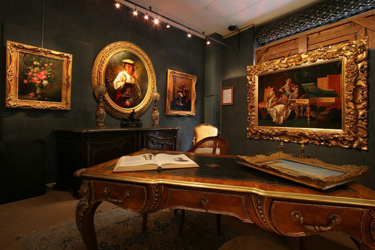 Un bureau antique orné dans une galerie d'art faiblement éclairée avec des peintures dans des cadres dorés.