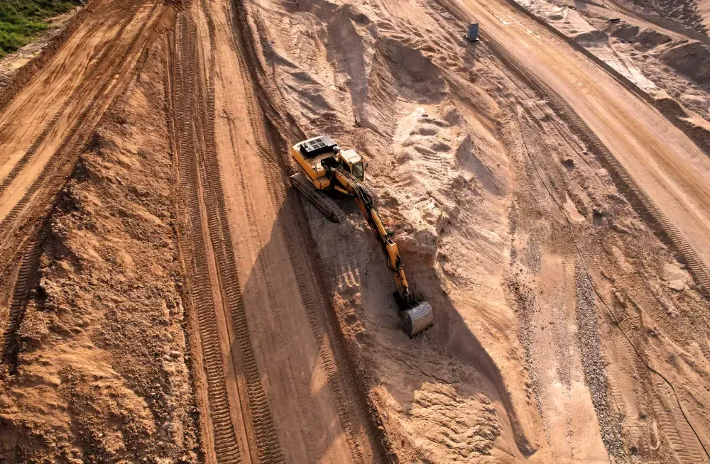 Excavadora en una pendiente de tierra marrón, cavando y moviendo tierra.