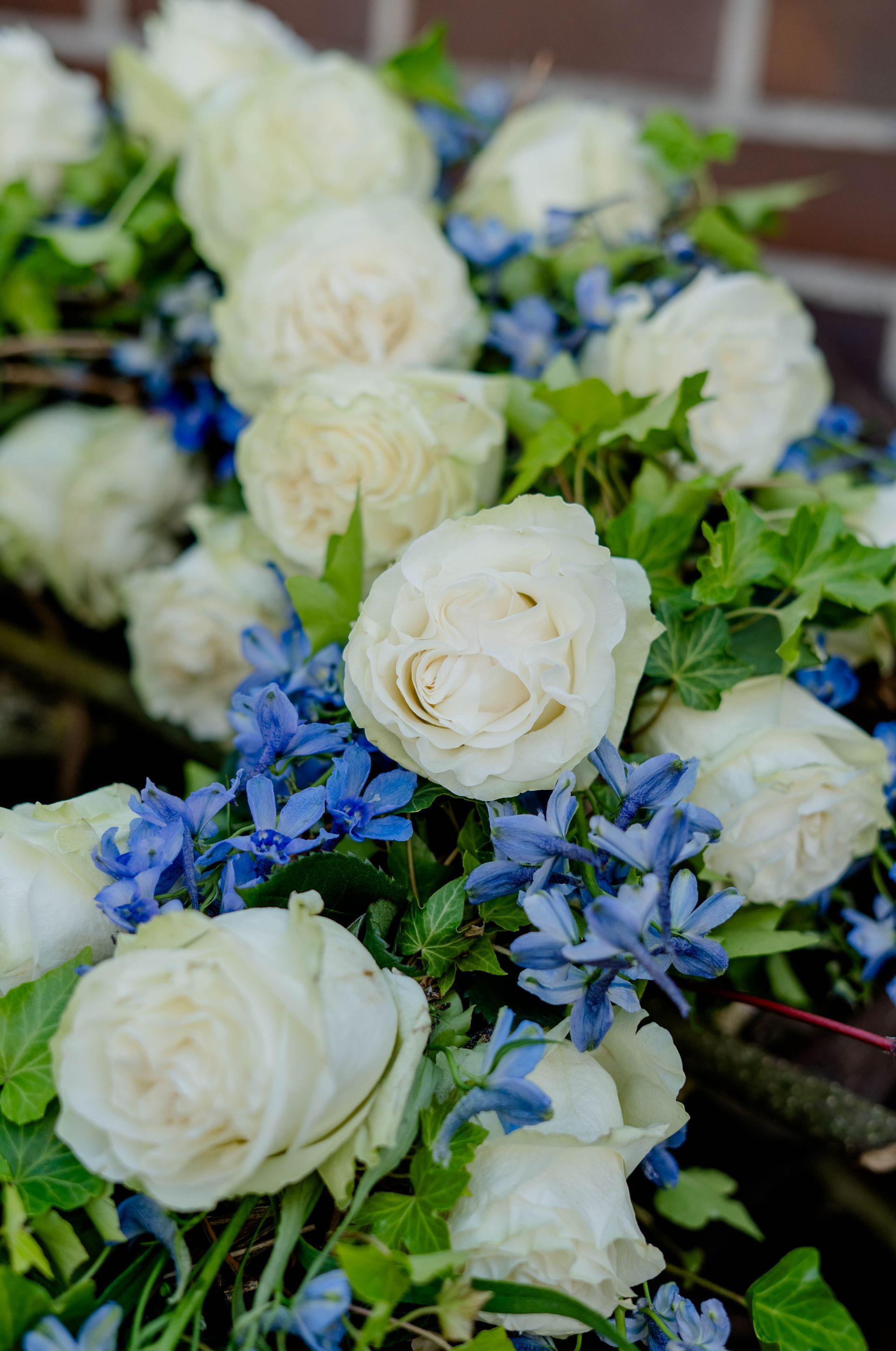 Weiße Rosen mit blauen Blüten in einem Blumenarrangement