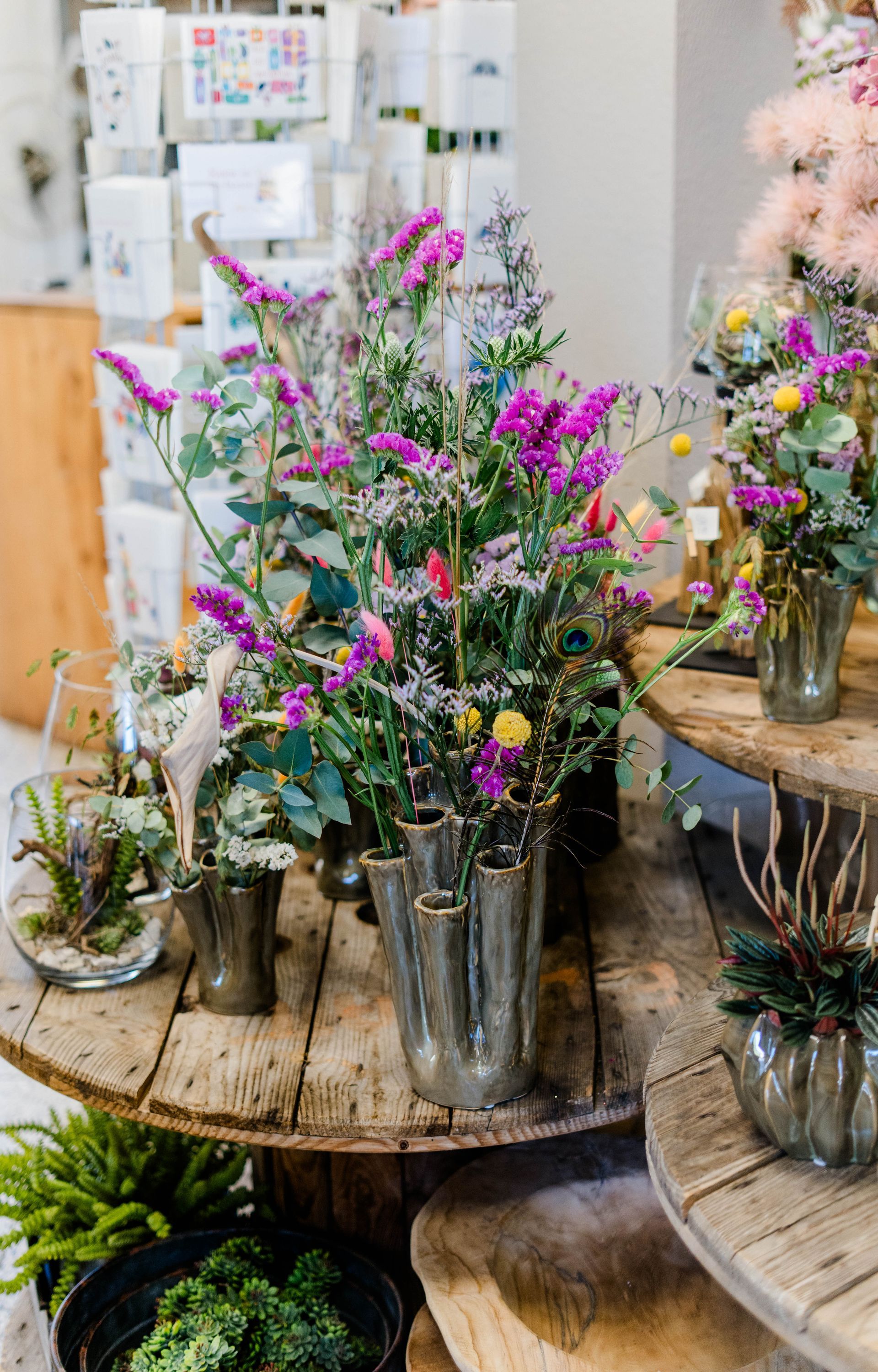Rustikale Blumenauslage mit farbenfrohen Wildblumensträußen in Glasvasen auf Holztischen