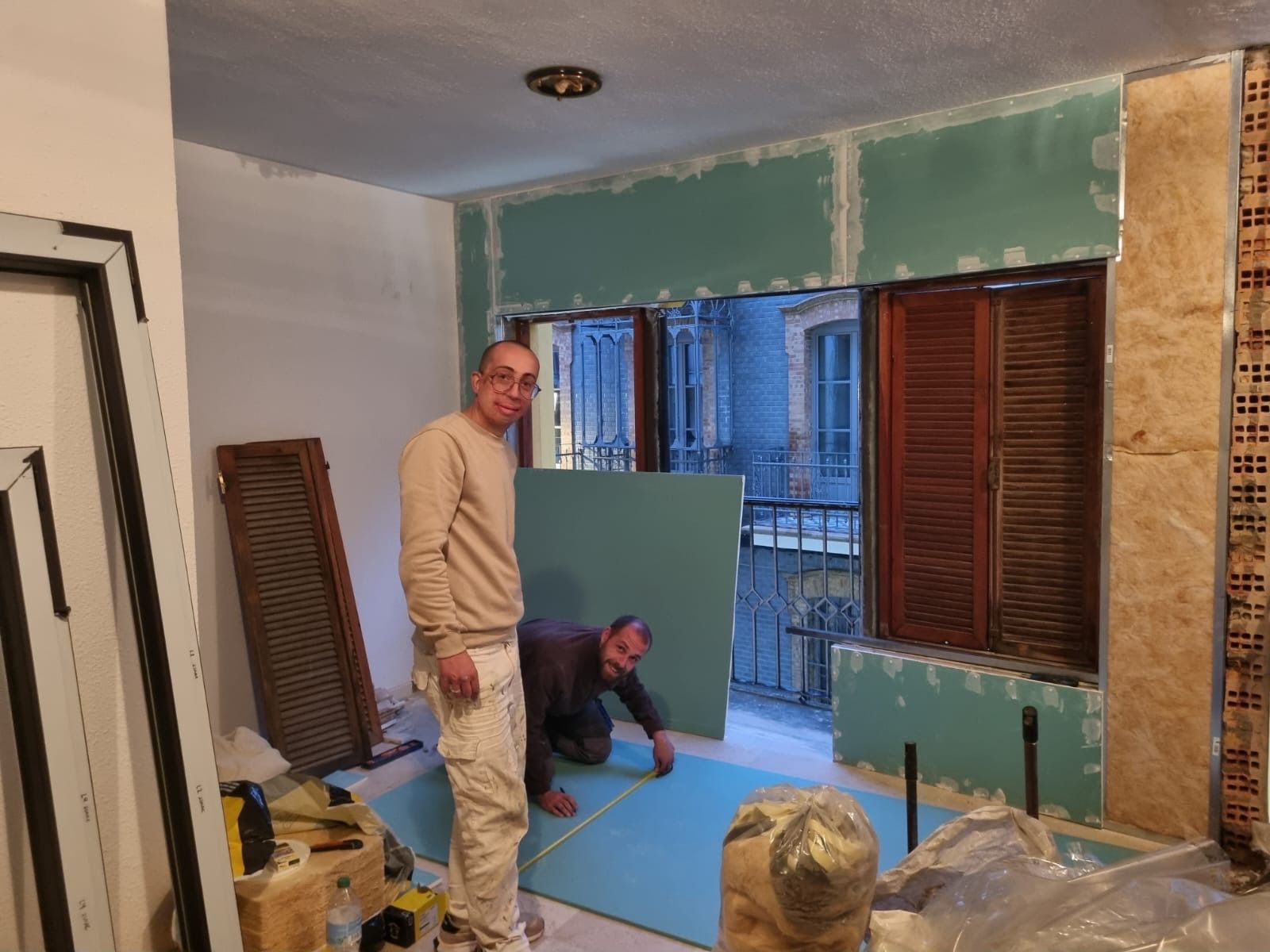 Dos hombres están trabajando en una pared de una habitación.