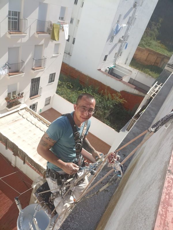 Un hombre está pintando el costado de un edificio.