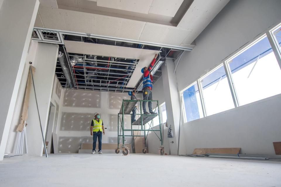 Ein Mann steht auf einem Gerüst in einem Raum im Bau.