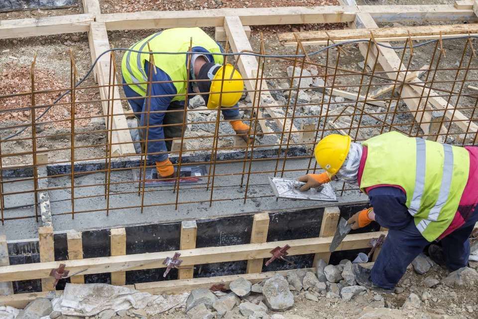 Ein paar Bauarbeiter arbeiten auf einer Baustelle.