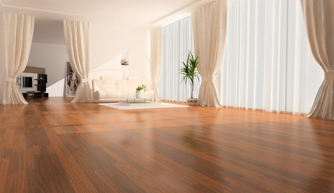 Pièce vide avec parquet, grandes fenêtres à rideaux blancs et un canapé en arrière-plan.