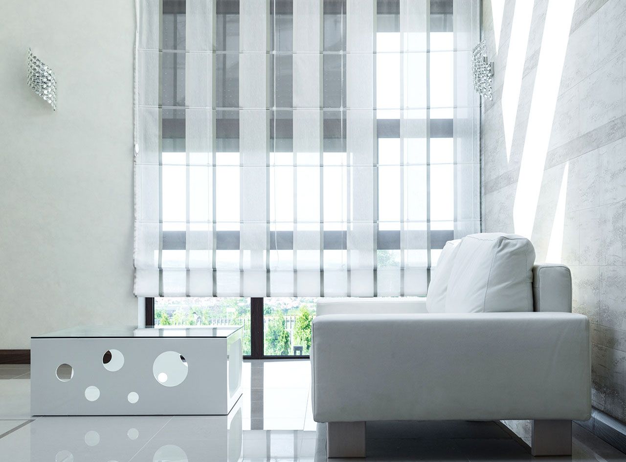 Salon moderne blanc avec canapé, table et stores rayés.
