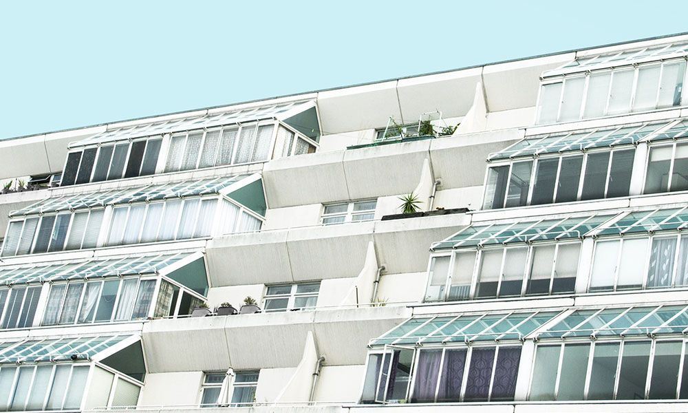 Immeuble d'appartements blanc avec de nombreux balcons à toits de verre.