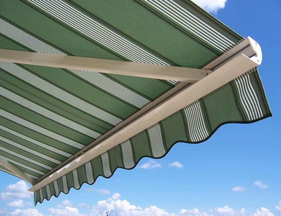 Store rétractable à rayures vertes et blanches sur fond de ciel bleu.