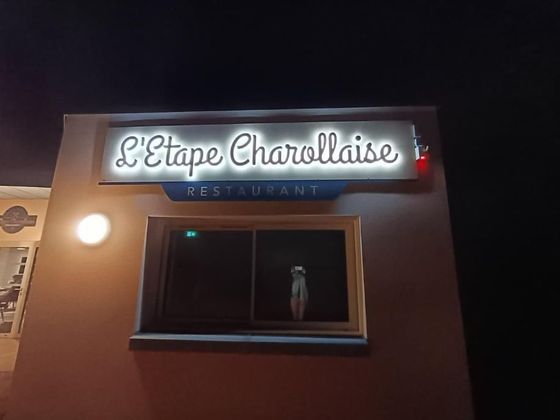 Enseigne du restaurant L'Étape Charollaise la nuit, avec des lettres blanches illuminées.