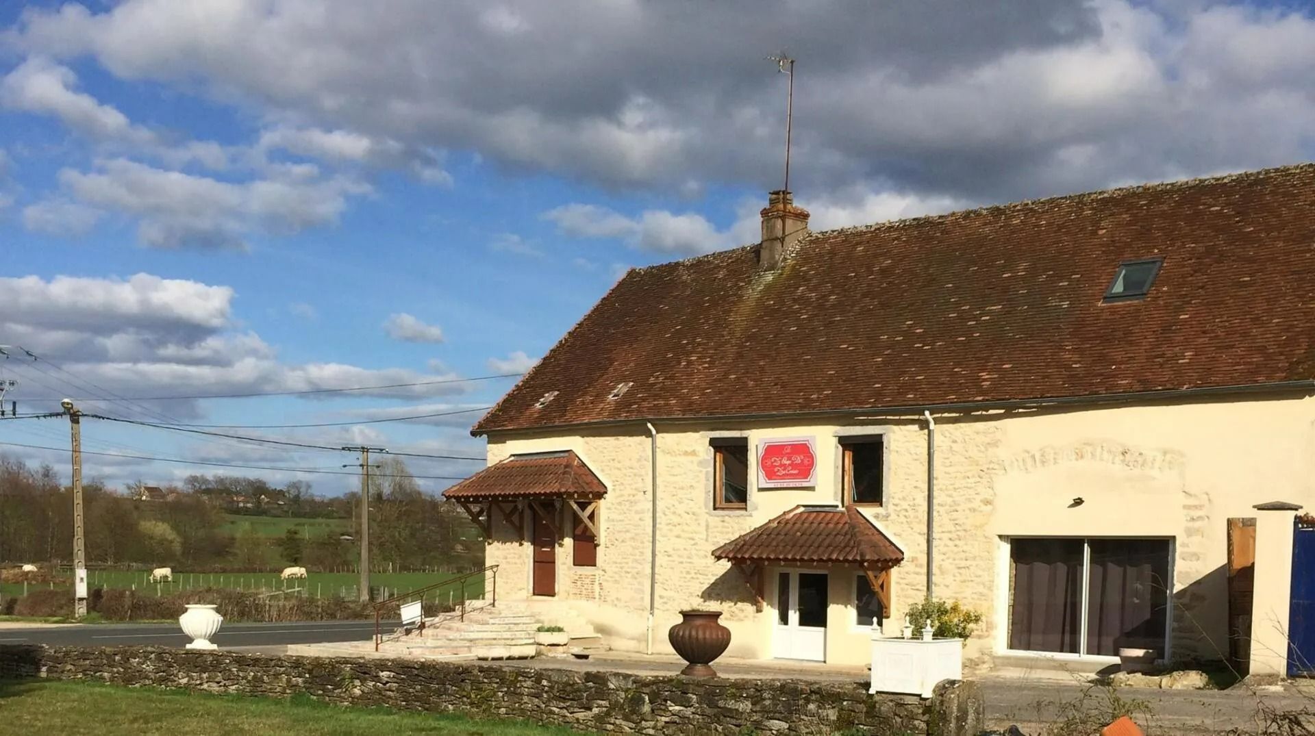 Bâtiment en pierre au toit de tuiles rouges, aux auvents bruns.