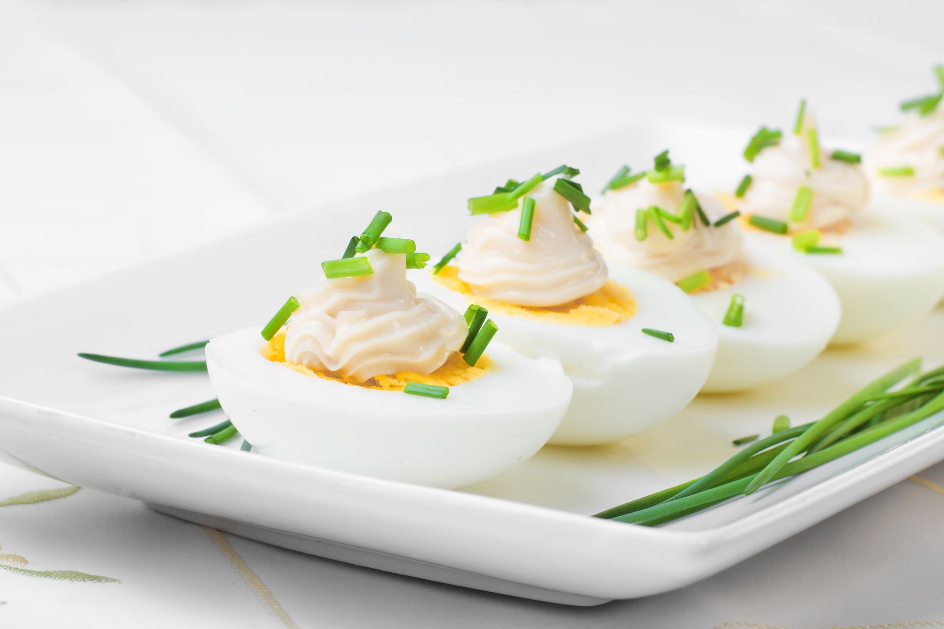 Œufs mimosa garnis de ciboulette et de paprika sur un plat blanc