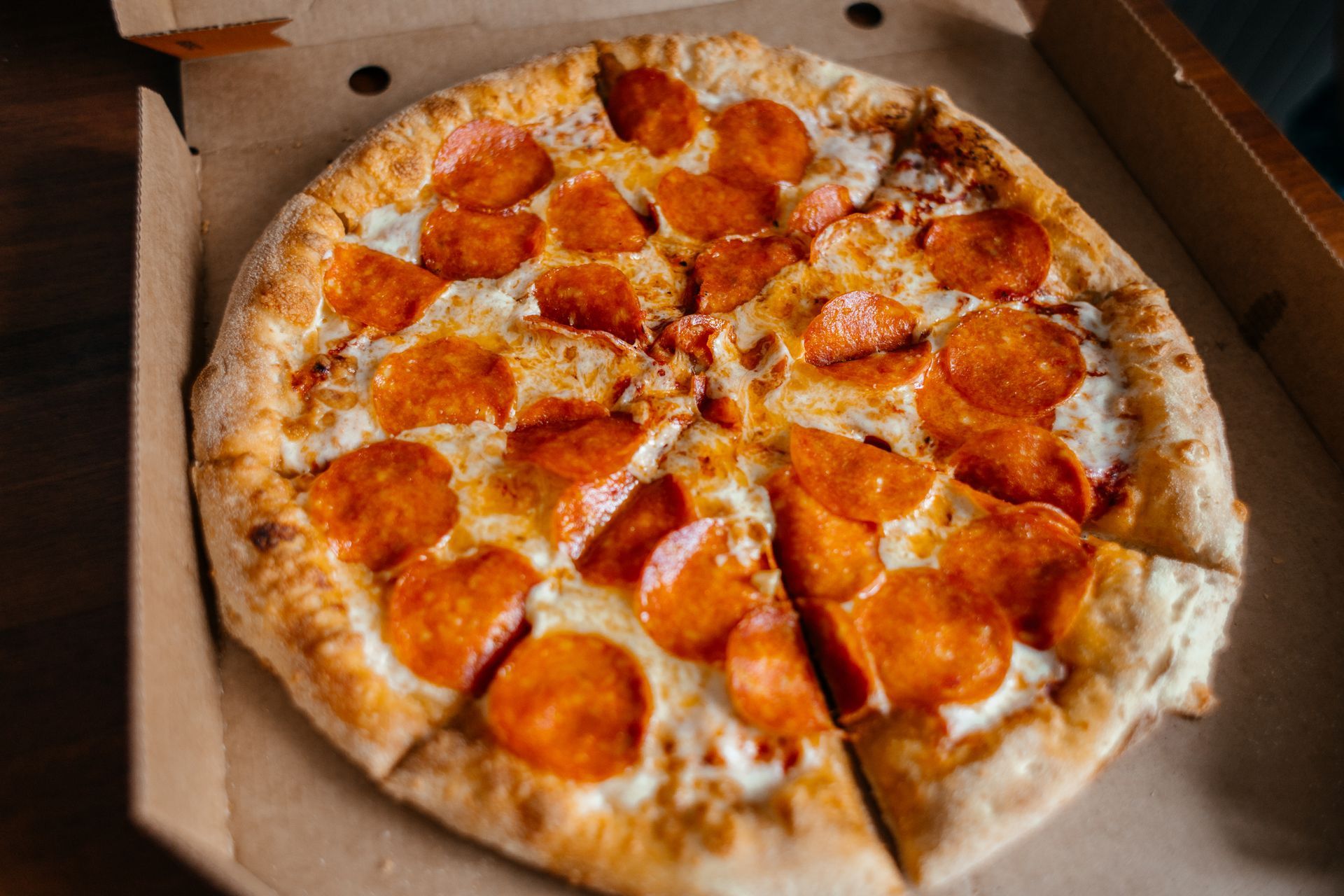 Pizza pepperoni dans une boîte en carton ouverte, coupée en parts