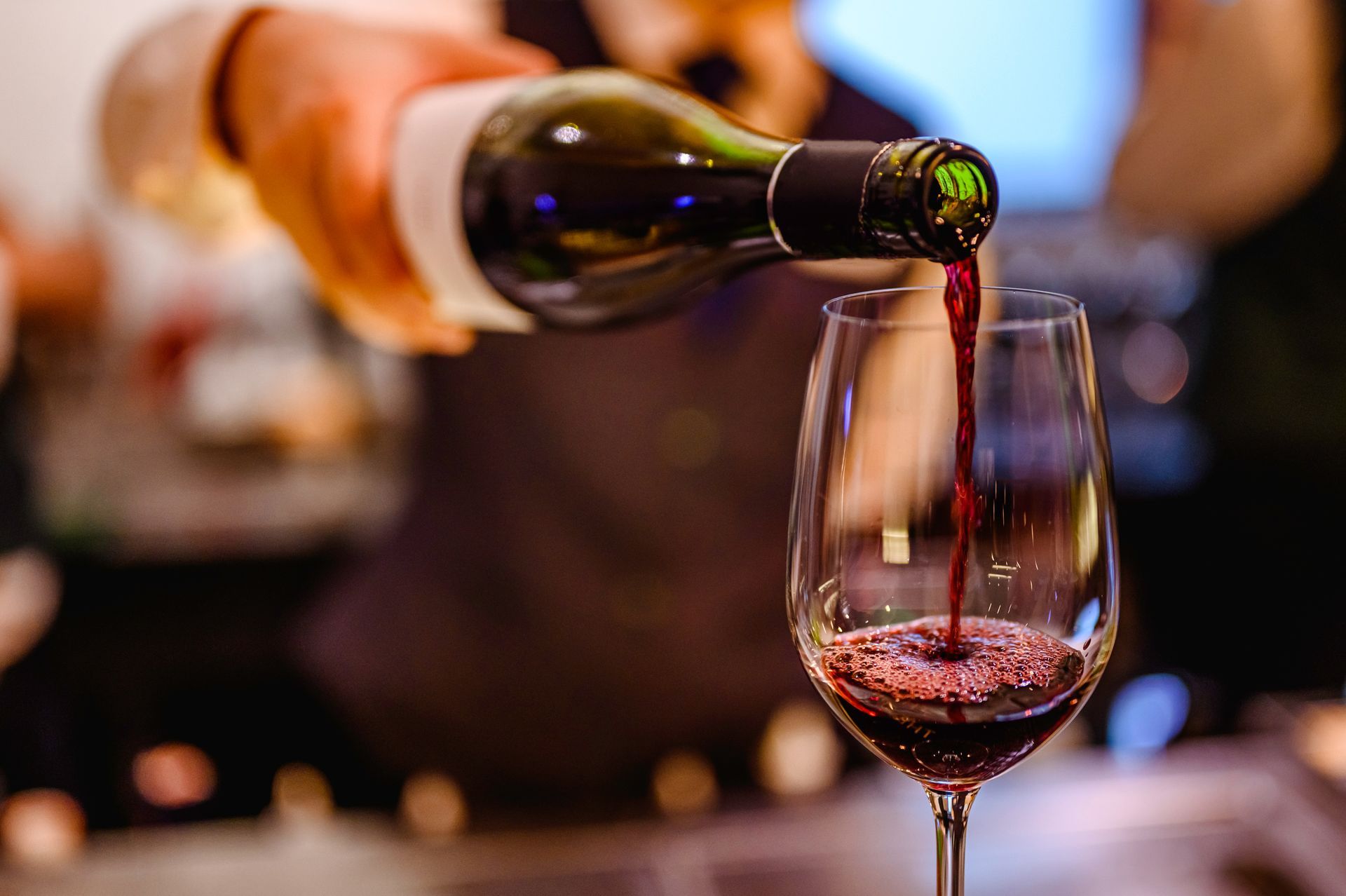 Du vin est versé dans un verre dans un bar à l'éclairage tamisé