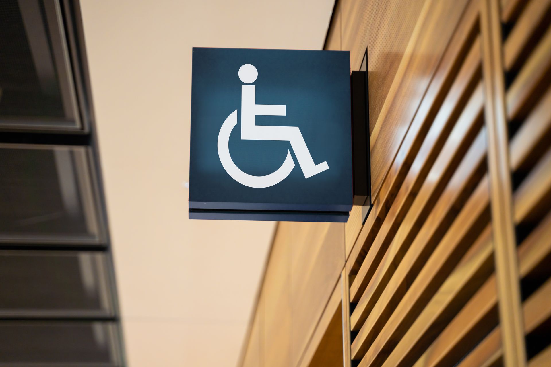 Panneau bleu d'accessibilité pour fauteuils roulants accroché dans un couloir avec un mur à lattes de bois