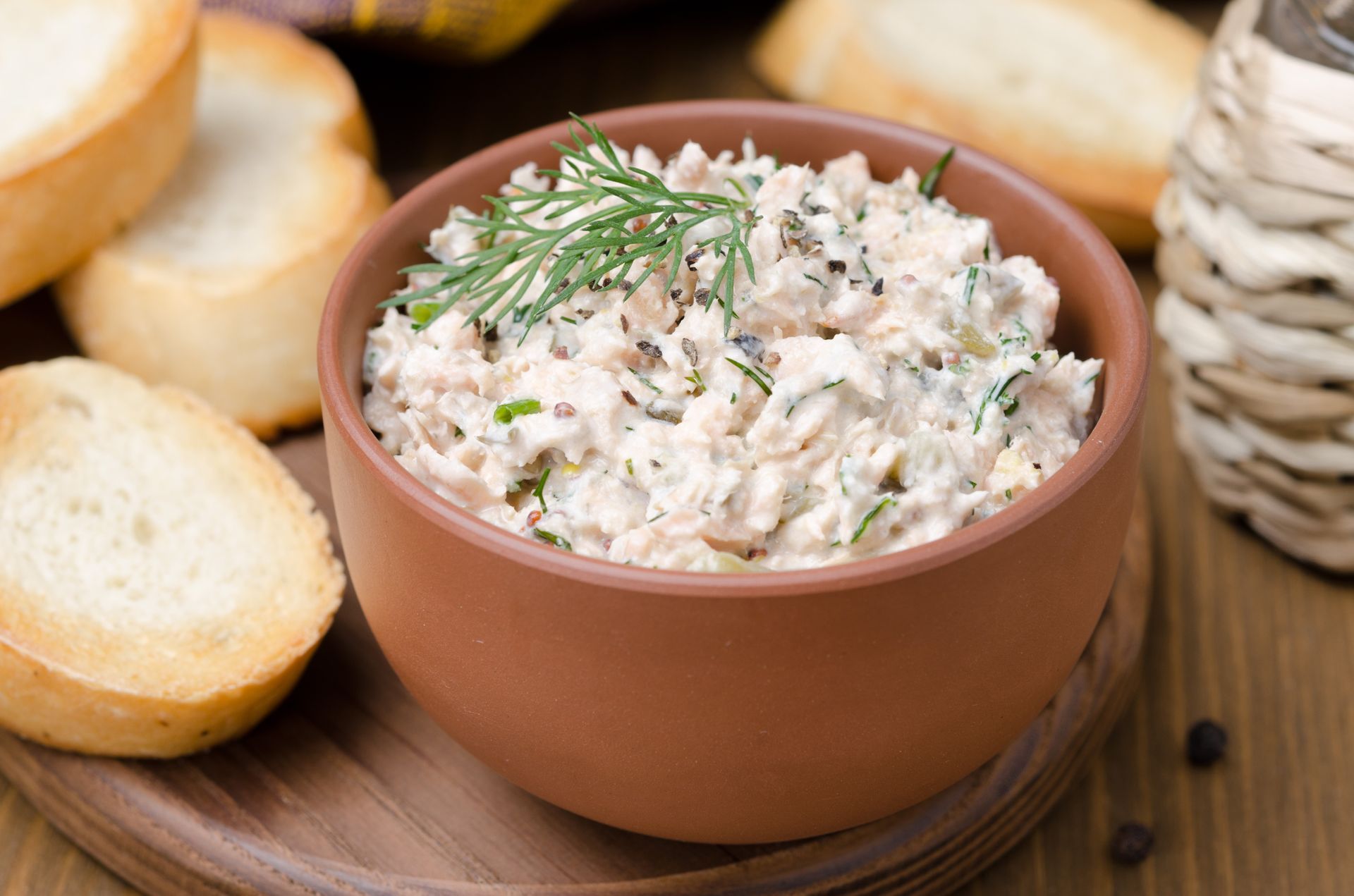 Pot de rillettes de poisson avec des tranches de baguette grillées sur une table en bois