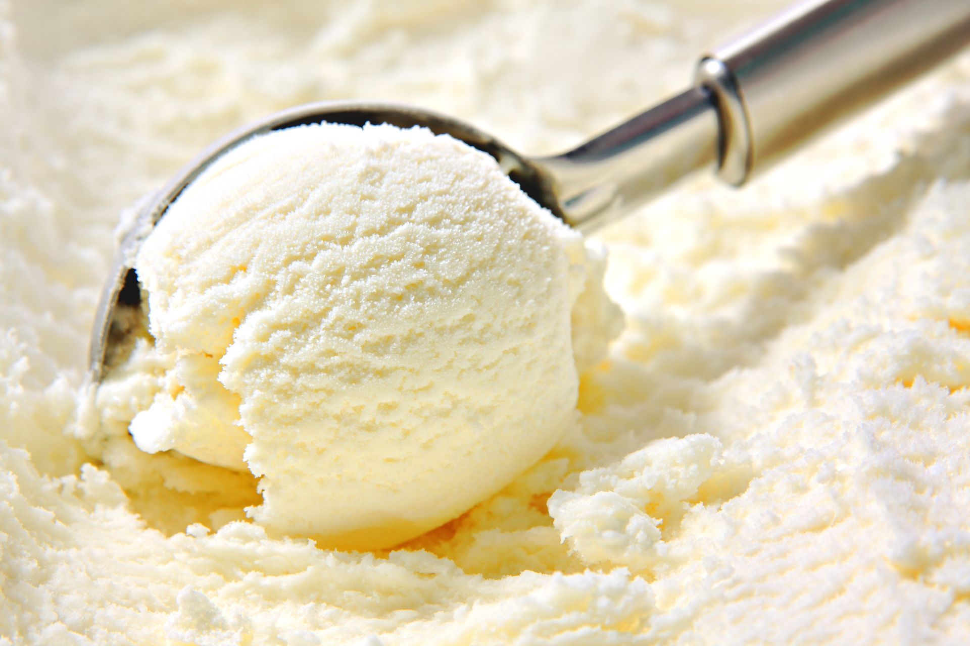 Cuillère à glace en métal contenant une boule de glace à la vanille sur un lit de glace