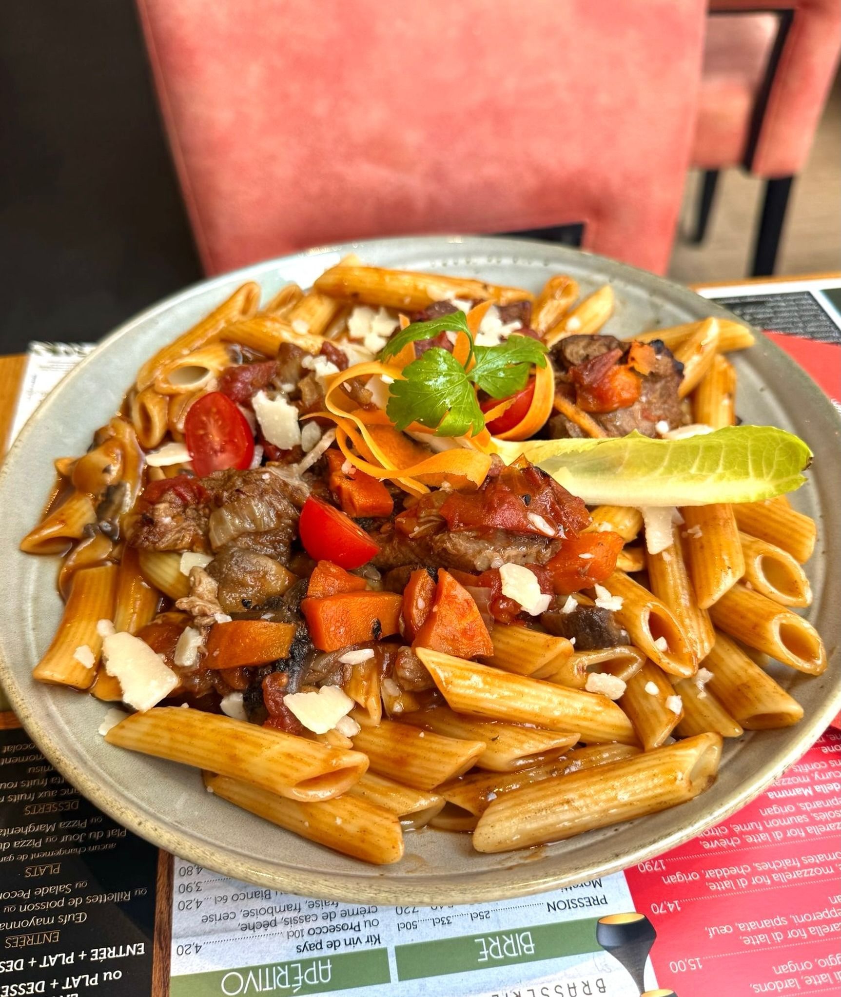 Assiette de penne à la viande, aux tomates et à la salade sur une table de restaurant