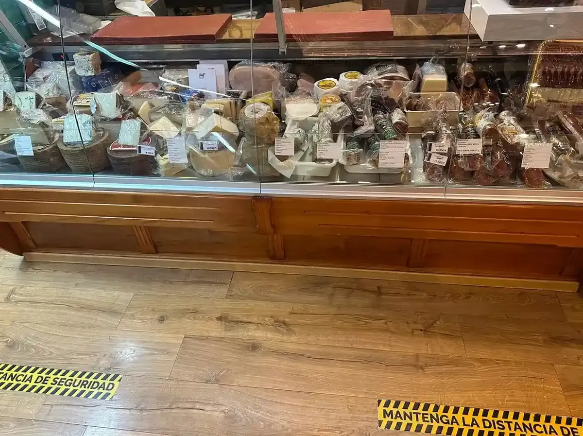 Vitrina de cristal con pasteles y postres variados sobre un suelo de madera.