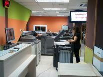 Una mujer está parada frente a una impresora en una oficina.