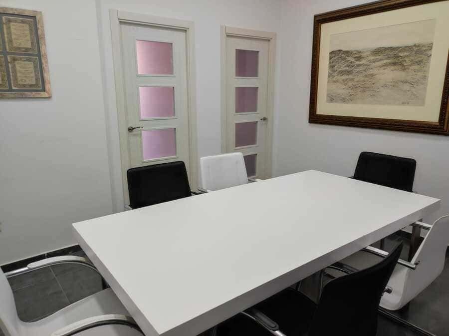 Una sala de conferencias con una larga mesa blanca y sillas.