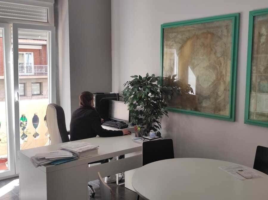 Una mujer está sentada en un escritorio en una oficina con una computadora.