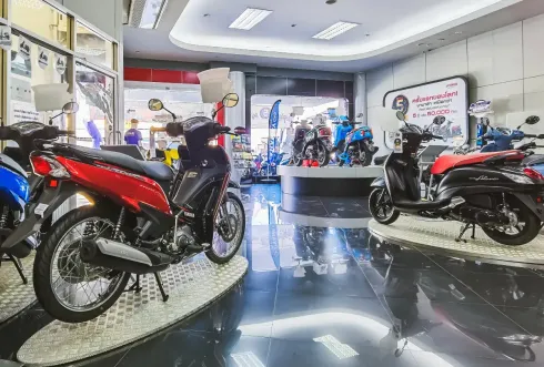 Sala de exposición de motocicletas con scooters rojas, negras y azules en exhibición. 