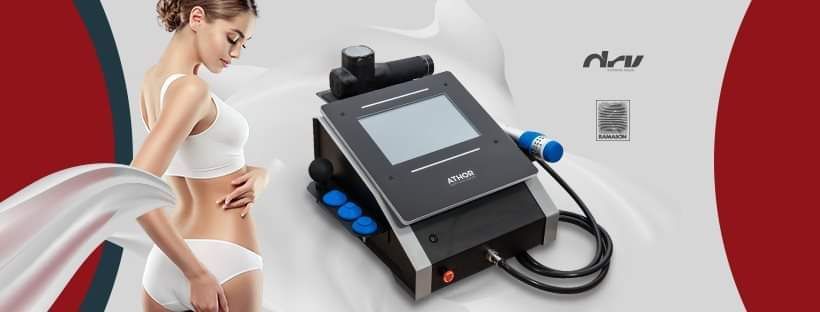 Una mujer en ropa interior blanca está de pie junto a una máquina sobre una mesa.