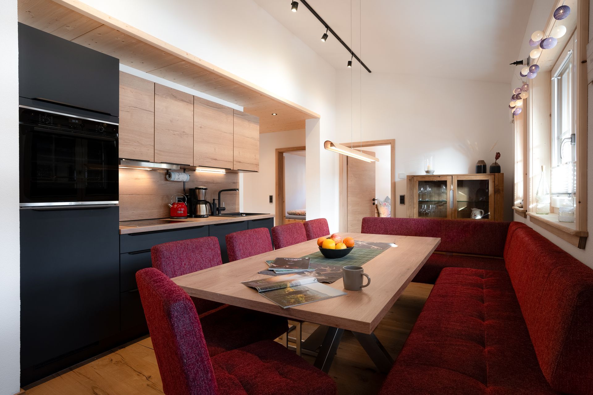Moderne Wohnküche mit roten Polstermöbeln, Holzdetails und gemütlicher Alpenatmosphäre
