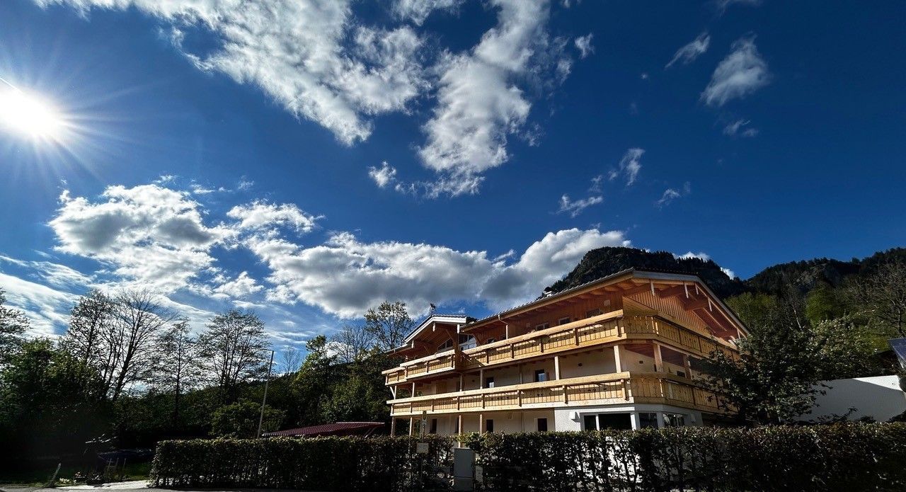 Ein großes Haus mit einem blauen Himmel und Wolken dahinter.
