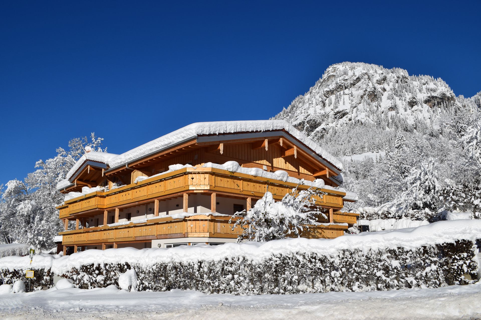 Ein großes Holzhaus ist von Bäumen und Bergen umgeben.