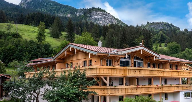 Ein großes Holzhaus ist von Bäumen und Bergen umgeben.